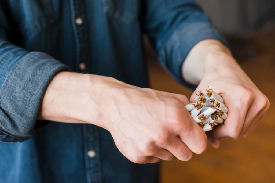 2026-05-31-tabak-close-up-human-hand-breaking-bundle-cigarettes.jpg